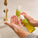 Person using Tropic’s Dessert Lime and Ginger Hand Wash, pumping the product into their hand under running water from a brass tap. A second bottle of the same product is visible in the background on the sink.